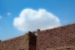 a brick wall with a cloud in the sky behind it .