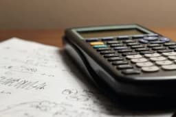 a calculator is sitting on top of a piece of paper drafting a business case.